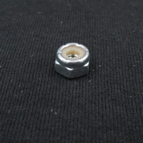 Small metal nut on black fabric surface, mechanical component for QRC Karts.